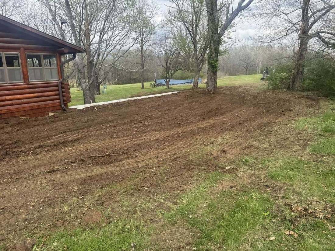 Regraded yard sloping away from a log home after drainage correction